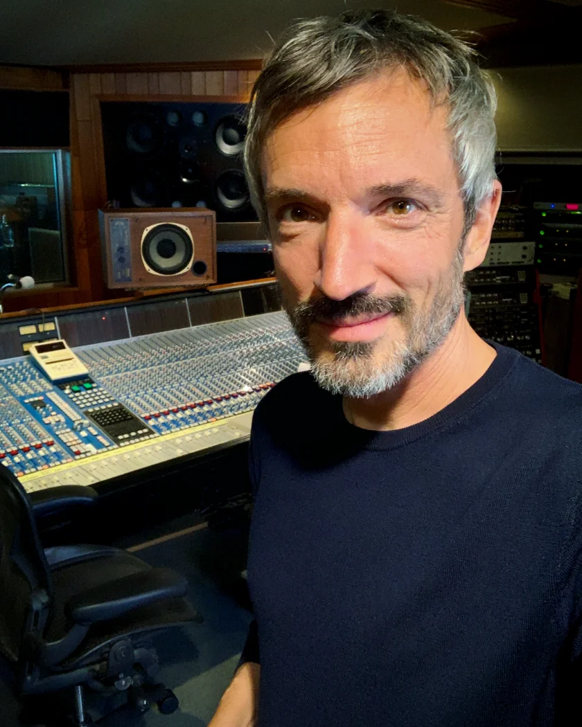 Clemens Matznik smiling in a studio control room, a large mixing console behind him